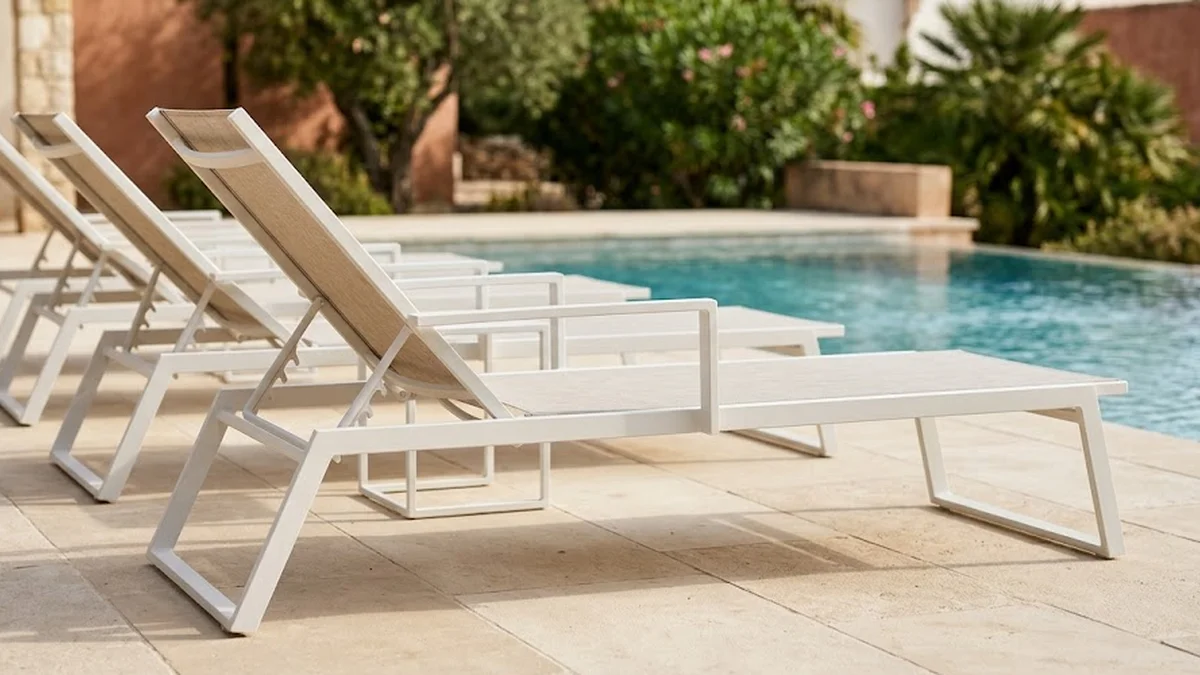 Alignement de bains de soleil en aluminium thermolaqué blanc le long d'une piscine d'hôtel
